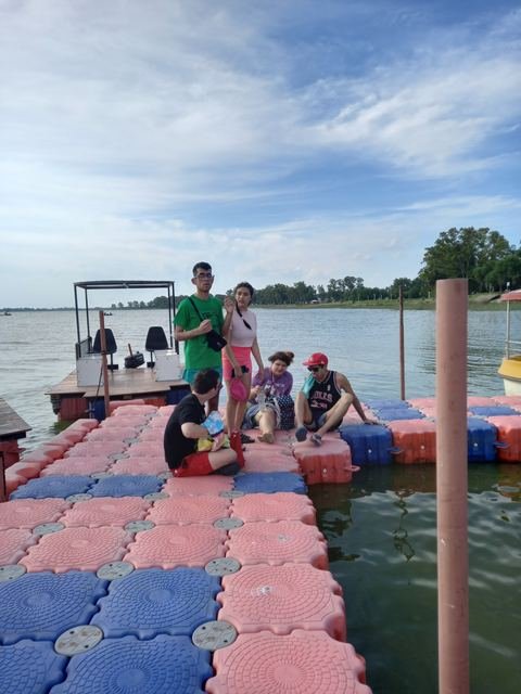 Participantes sentados en una pasarela flotante sobre el agua