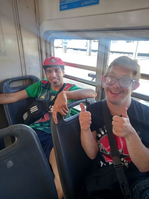 Dos participantes viajando en colectivo, con el pulgar hacia arriba