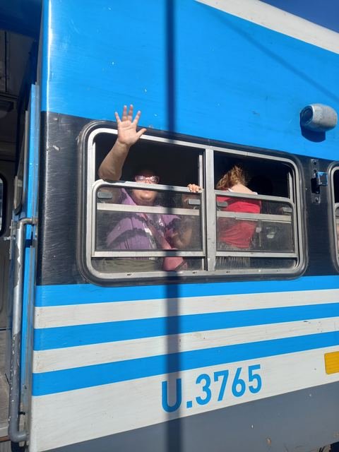 Una participante saludando por la ventanilla del colectivo
